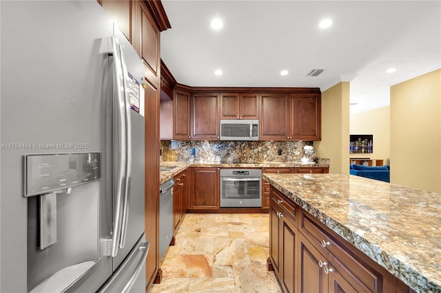 kitchen with visible vents, light stone counters, stone finish flooring, stainless steel appliances, and backsplash