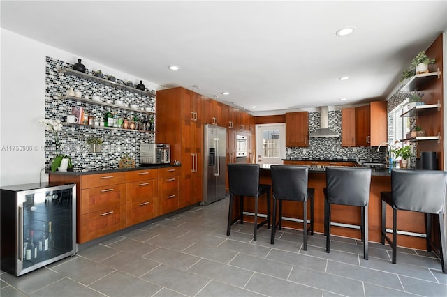 kitchen with beverage cooler, stainless steel fridge with ice dispenser, a peninsula, wall chimney range hood, and open shelves