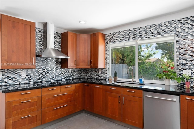 kitchen with a sink, wall chimney range hood, stainless steel dishwasher, backsplash, and dark stone countertops