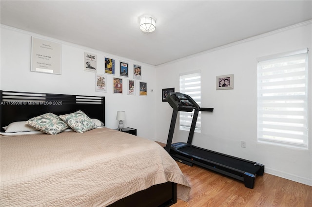 bedroom featuring crown molding, baseboards, and wood finished floors