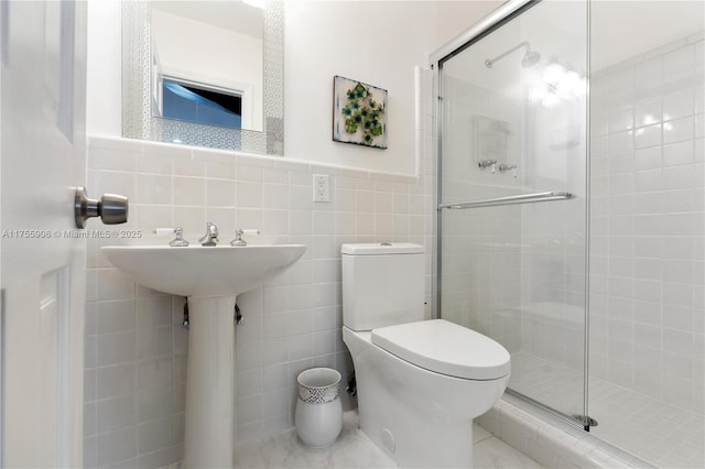 bathroom with a stall shower, a wainscoted wall, tile walls, and toilet