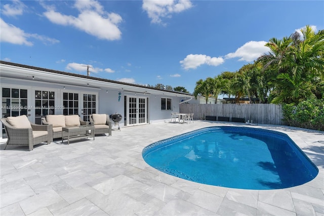 view of pool featuring french doors, grilling area, a patio area, a fenced backyard, and an outdoor living space