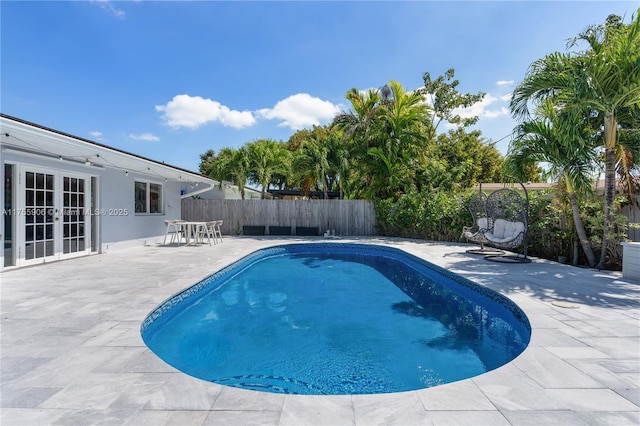 view of swimming pool with french doors, a patio area, a fenced backyard, and a fenced in pool