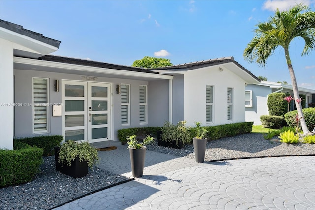 view of exterior entry featuring french doors and stucco siding