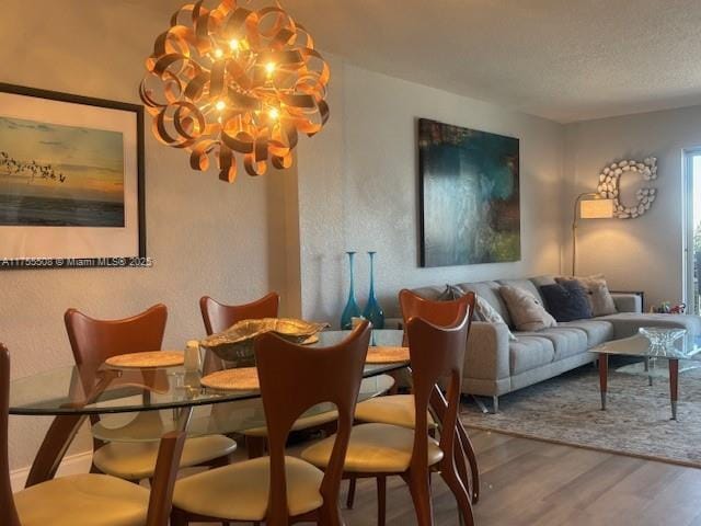 dining room featuring a textured ceiling, an inviting chandelier, and wood finished floors