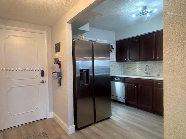 kitchen with light wood finished floors, a sink, stainless steel appliances, light countertops, and dark brown cabinets