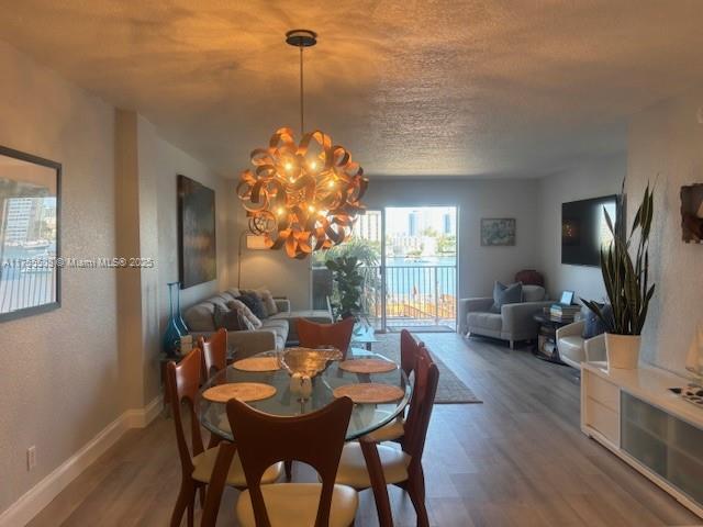 dining area with baseboards, a notable chandelier, wood finished floors, and a textured ceiling