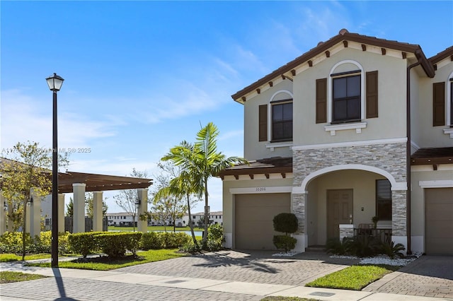 view of front of house with a garage, stone siding, decorative driveway, and stucco siding