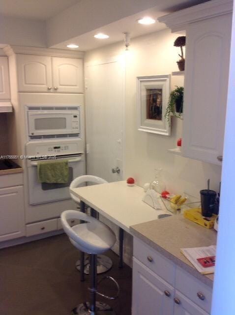 kitchen featuring white appliances, white cabinets, dark wood-style floors, light countertops, and recessed lighting