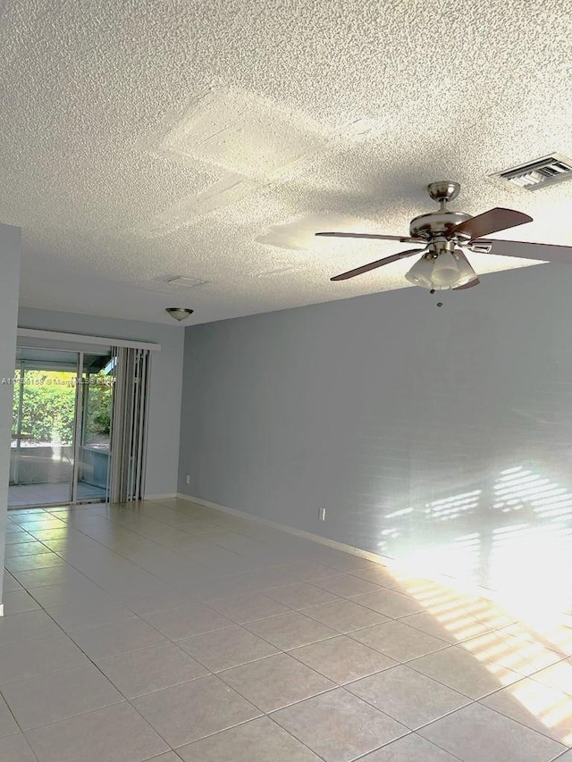 spare room with light tile patterned floors, a textured ceiling, a ceiling fan, visible vents, and baseboards