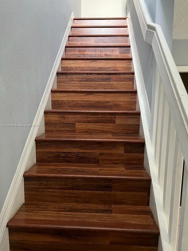 stairs with a textured ceiling and a textured wall