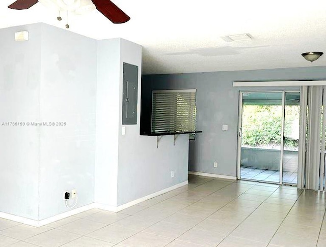 empty room with electric panel, baseboards, a ceiling fan, and light tile patterned flooring