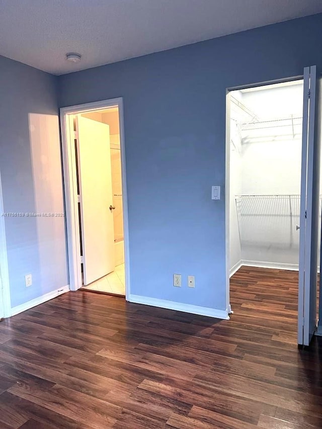 unfurnished bedroom with a closet, wood finished floors, and baseboards