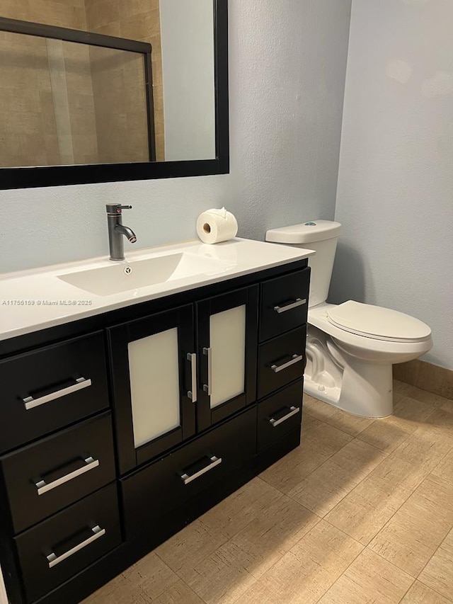 full bathroom with toilet, a stall shower, and vanity