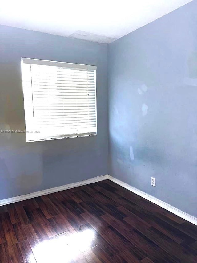 spare room featuring wood finished floors and baseboards