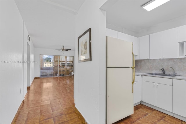 kitchen featuring a sink, white cabinetry, light countertops, backsplash, and freestanding refrigerator