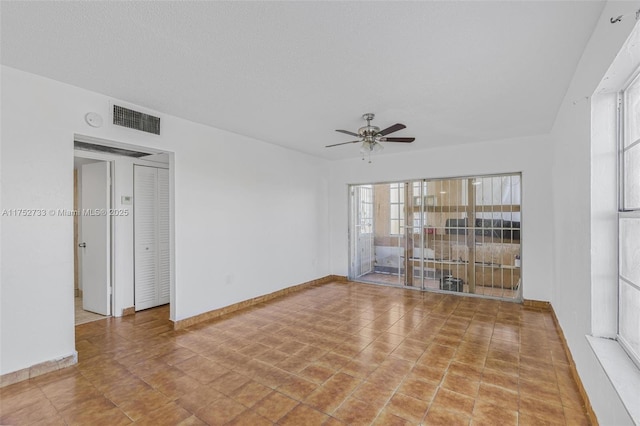 unfurnished room with a ceiling fan, visible vents, a textured ceiling, and baseboards