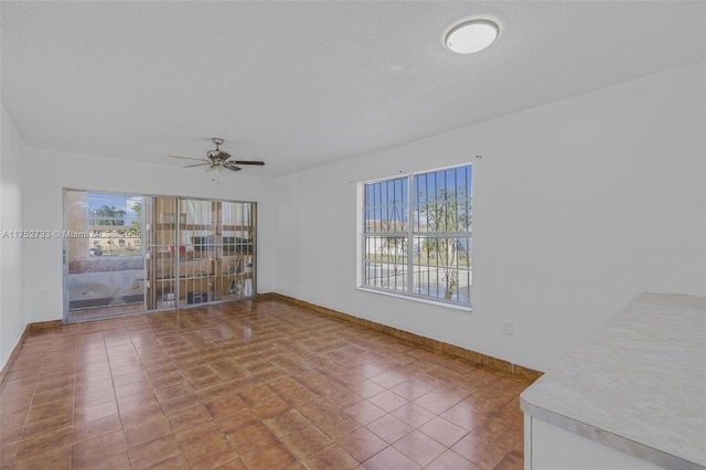 spare room featuring ceiling fan, a textured ceiling, and baseboards