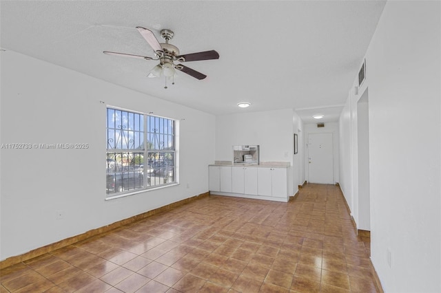 spare room with ceiling fan, a textured ceiling, visible vents, and baseboards