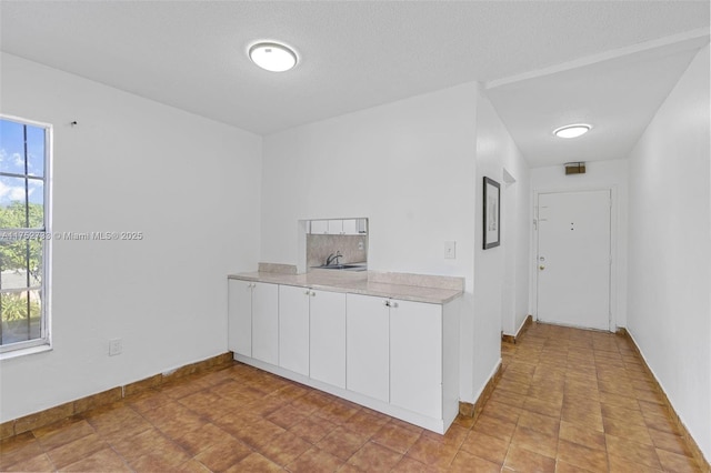 spare room featuring a textured ceiling and baseboards