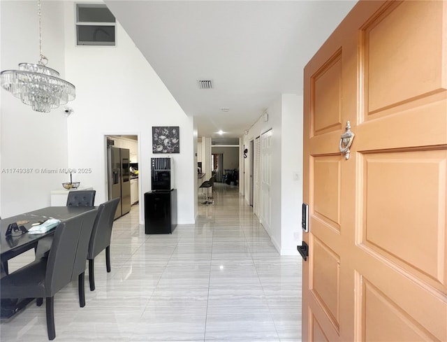 hallway featuring a barn door, visible vents, and a notable chandelier