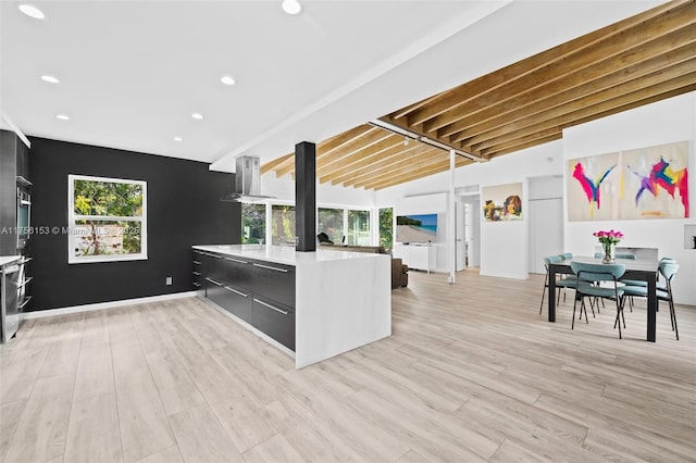 kitchen featuring lofted ceiling with beams, light wood-style flooring, modern cabinets, extractor fan, and light countertops