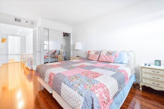 bedroom featuring a closet, visible vents, french doors, and wood finished floors