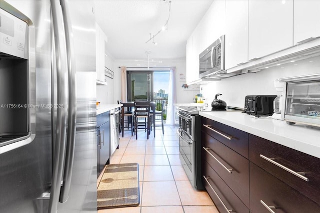 kitchen with white cabinetry, appliances with stainless steel finishes, light tile patterned flooring, light countertops, and dark brown cabinets