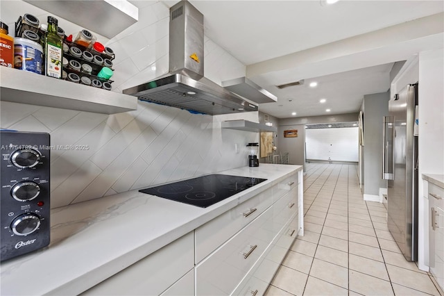 2413 Sugarloaf Ln, Fort Lauderdale, FL 33312 - kitchen with black electric stovetop, freestanding refrigerator, white cabinetry, light tile patterned floors, and island range hood