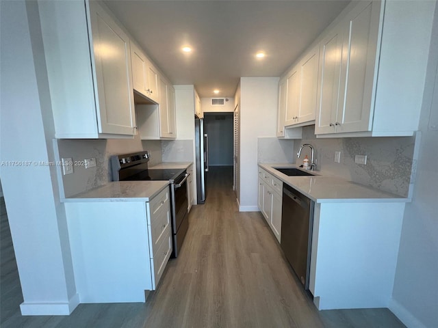 kitchen featuring light wood finished floors, white cabinetry, appliances with stainless steel finishes, and a sink