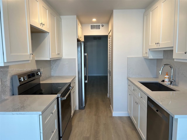 kitchen with visible vents, appliances with stainless steel finishes, white cabinetry, a sink, and light wood-type flooring