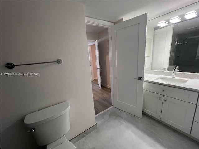 bathroom featuring concrete flooring, baseboards, vanity, and toilet