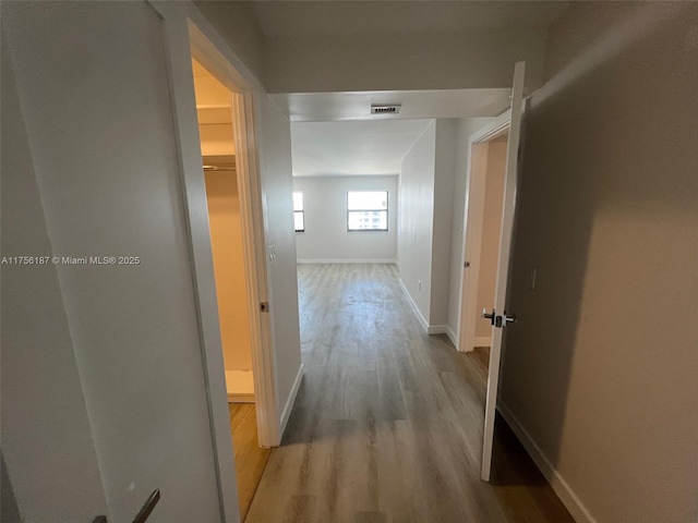 hallway featuring visible vents, baseboards, and wood finished floors