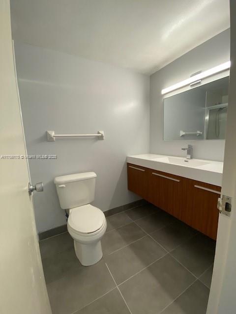 bathroom featuring tile patterned flooring, baseboards, vanity, and toilet