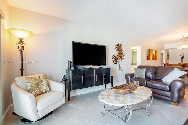 living room featuring light tile patterned floors, a textured ceiling, and baseboards