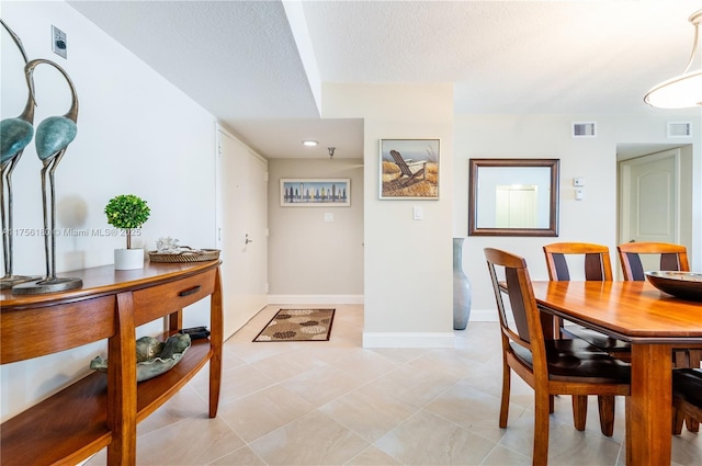 dining room featuring light tile patterned floors, baseboards, visible vents, and a textured ceiling