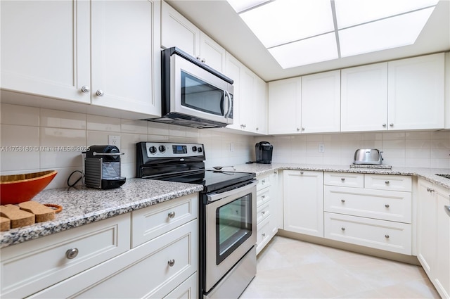 kitchen with light stone counters, appliances with stainless steel finishes, white cabinets, and tasteful backsplash