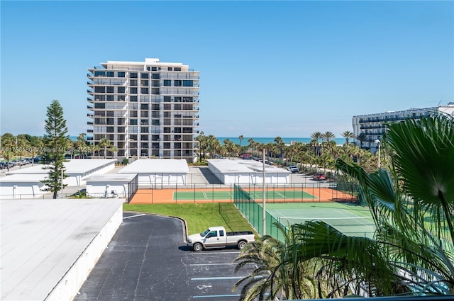 view of building exterior with uncovered parking, a water view, and fence