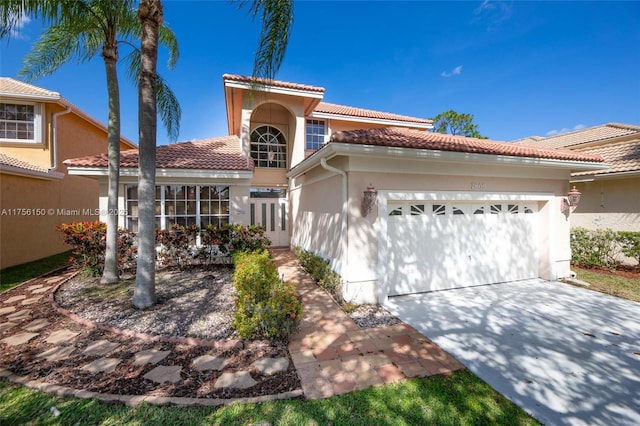 mediterranean / spanish house with an attached garage, a tile roof, and stucco siding