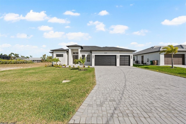 prairie-style home with a garage, decorative driveway, a front yard, and stucco siding