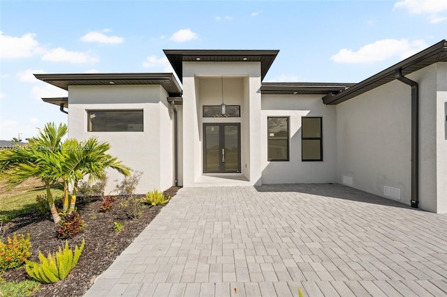 view of exterior entry with a patio, crawl space, visible vents, and stucco siding