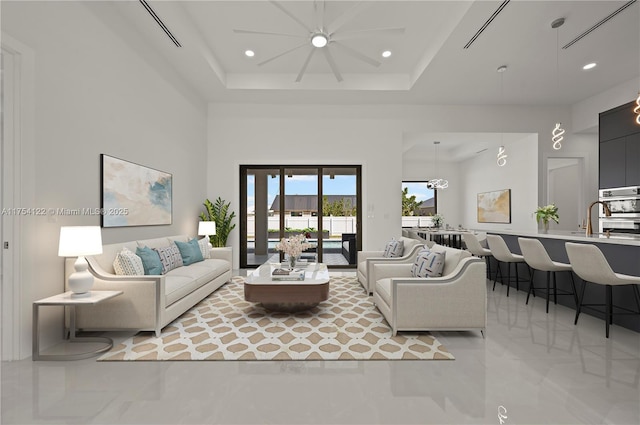 living area with a high ceiling, a tray ceiling, and recessed lighting