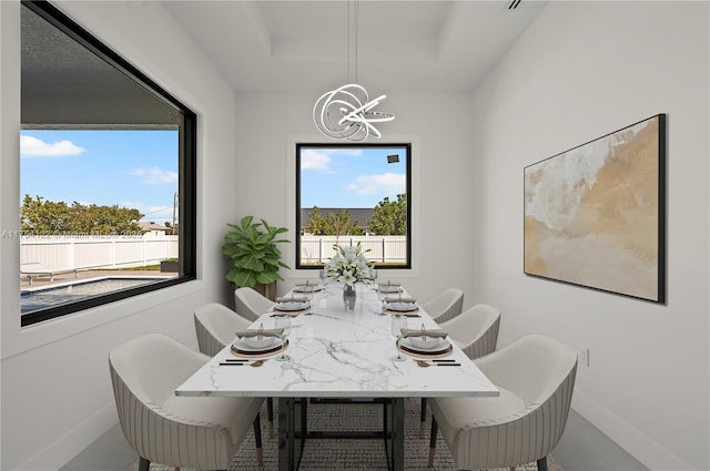 dining area featuring a chandelier, a tray ceiling, and baseboards