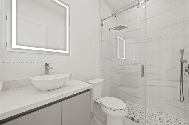 full bathroom featuring toilet, a marble finish shower, and vanity