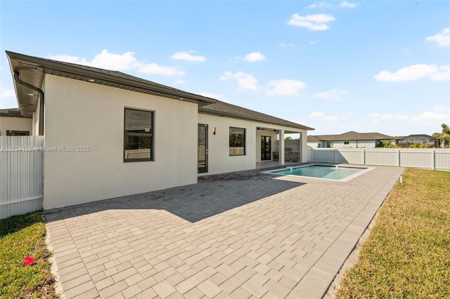 rear view of house with a patio, a fenced backyard, a lawn, a fenced in pool, and stucco siding