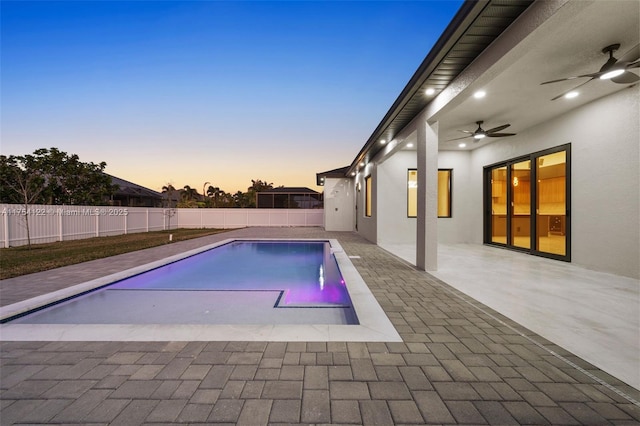 pool at dusk with a fenced in pool, a patio area, a fenced backyard, and ceiling fan