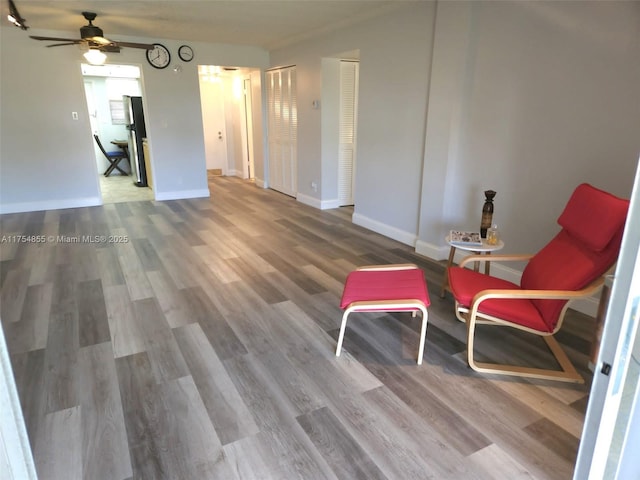 living area featuring a ceiling fan, wood finished floors, and baseboards