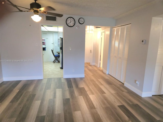 spare room featuring visible vents, ceiling fan, a textured ceiling, wood finished floors, and baseboards