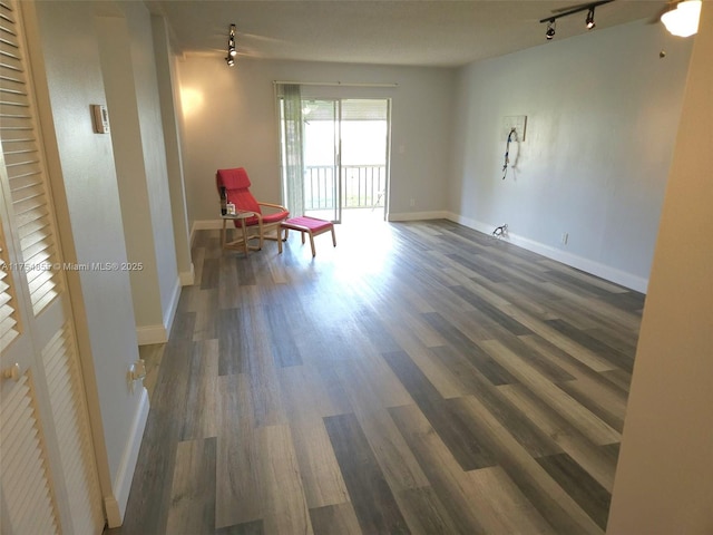 unfurnished room with track lighting, wood finished floors, and baseboards