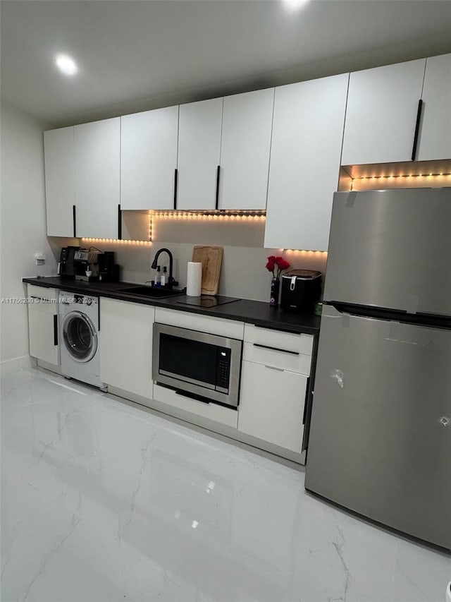 kitchen with washer / dryer, appliances with stainless steel finishes, marble finish floor, and a sink